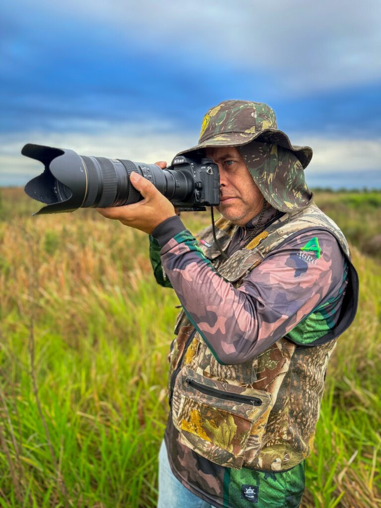 Condutor em formação fotografando aves com teleobjetiva no campo nativo do Vale das Águas, MS
