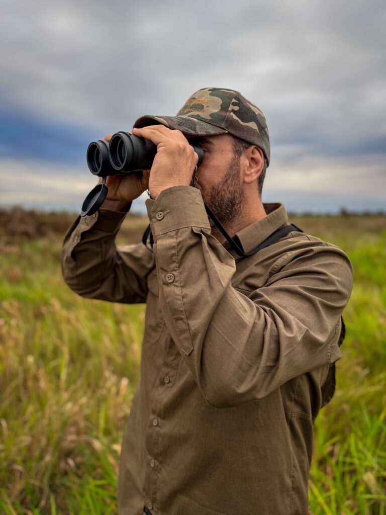 Condutor em formação observando aves com binóculo no campo