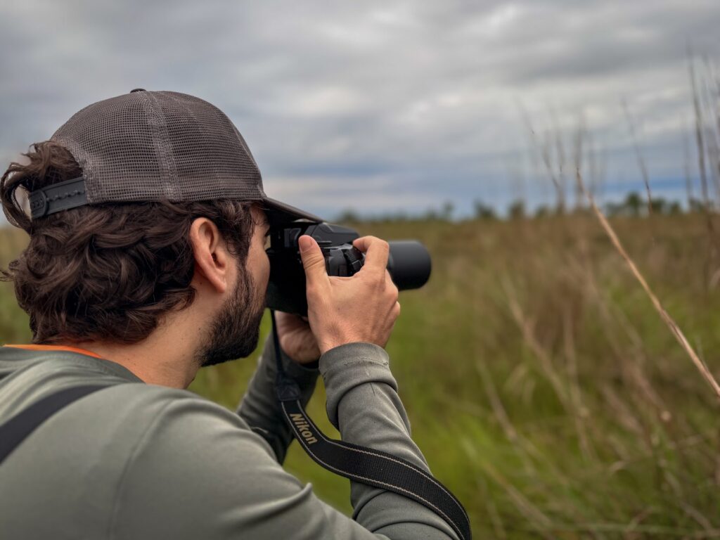 Participante fotografando aves durante prática de campo do curso de condutores